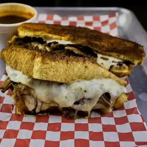 Birria melt on golden Texas Toast with melted cheese and beef birria served with consomé — Takitos Con Sabor TX