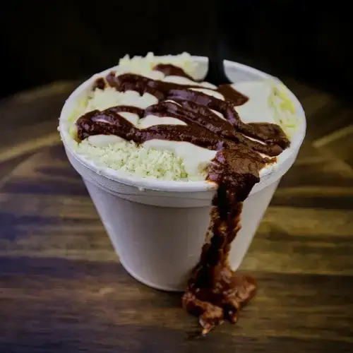 Mexican street corn elote in a cup topped with cotija cheese, crema, butter and chile — Takitos Con Sabor TX