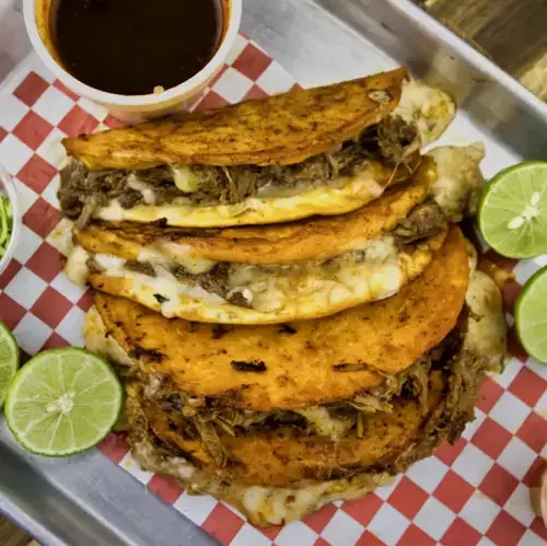 Quesabirria tacos on flour tortilla with melted cheese and birria consomé dipping cup — Takitos Con Sabor TX